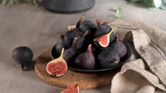 Fresh Ripe Purple Figs in a Dark Ceramic Bowl with Linen Accent
