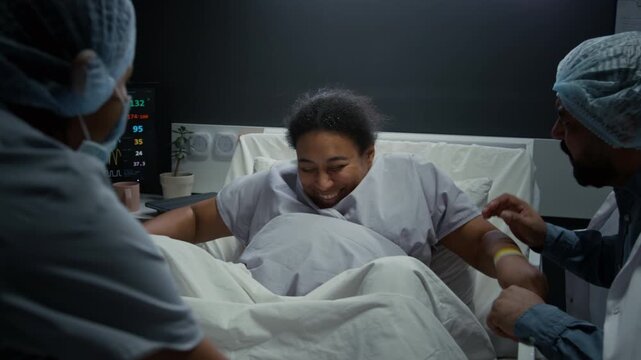 Black pregnant woman pushing during labor in hospital bed with husband and doctor providing support. Footage is suitable for maternity care and childbirth education videos