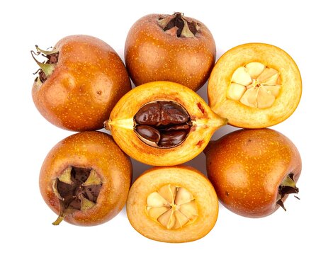 View of whole and halved medlar fruits arranged symmetrically, showing star-shaped cores