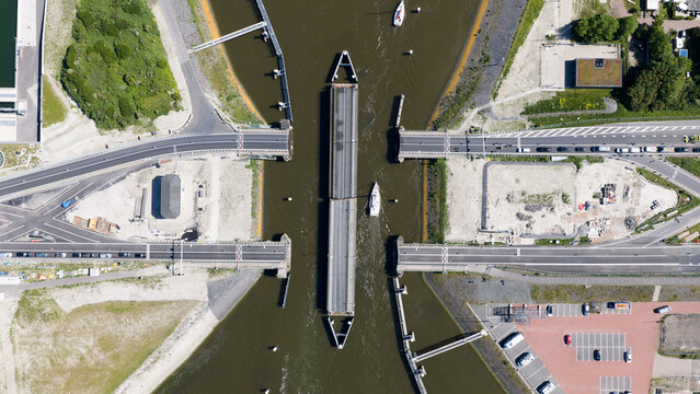 Aerial view of the Afsluitdijk swing bridge open for a boat to pass through with cars waiting on the road in Breezanddijk, Friesland, Netherlands.