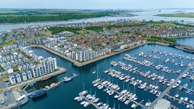 Aerial view of Saint Mary's Island featuring modern waterfront apartments and sailboats moored in the marina under a clear sky in Rochester, England, United Kingdom.