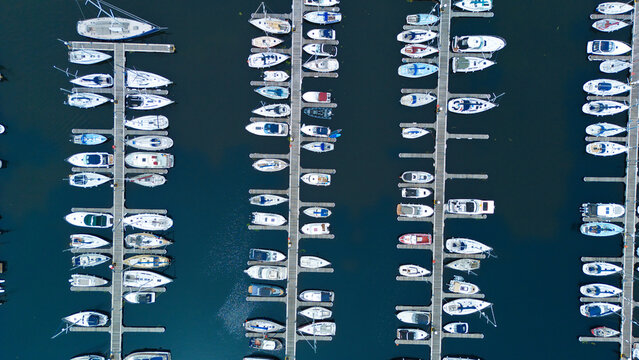 Aerial view of numerous white boats and yachts moored at wooden piers in the marina of Saint Mary's Island in Rochester, England, United Kingdom.