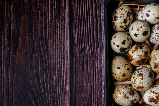 Top view of fresh quail eggs in square frying pan on wooden table with copy space