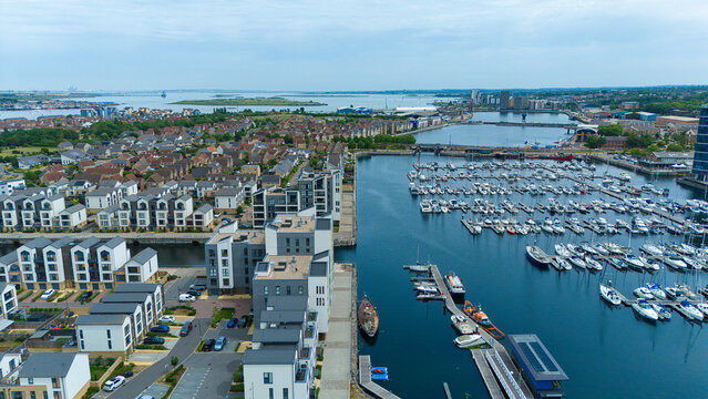 Aerial view of Saint Mary's Island marina with modern residential buildings and numerous yachts moored in the docks under an overcast sky in Rochester, England, United Kingdom.