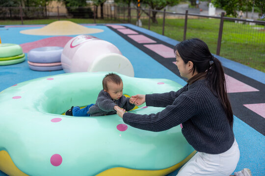 Happy mother playing with her little baby inside a giant colorful donu