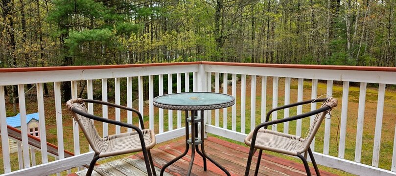 Cozy outdoor patio furniture on a balcony offering a tranquil view of the lush forest