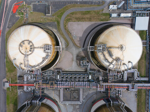 Aerial view of Grain LNG storage tanks with large circular domes and an intricate network of silver pipes in Wallend, England, United Kingdom.