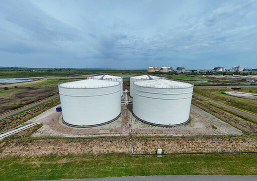 Aerial view of Grain LNG terminal with large white storage tanks and industrial infrastructure under a cloudy sky in Wallend, England, United Kingdom.