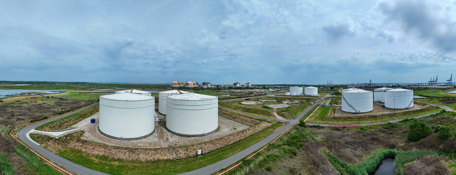 Aerial view of Grain LNG terminal featuring large white storage tanks and industrial infrastructure across a flat coastal landscape under a cloudy sky in Wallend, England, United Kingdom.