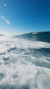 Powerful ocean wave cresting and crashing with turquoise water and white foam under a clear blue sky, dynamic ocean movement