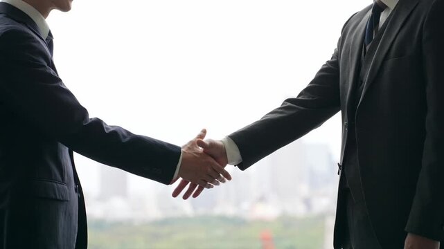 A group of business people shaking hands against a city backdrop.