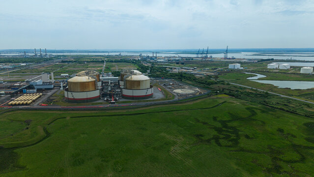 Aerial view of Grain LNG terminal with large storage tanks and industrial infrastructure surrounded by green fields in Wallend, England, United Kingdom.