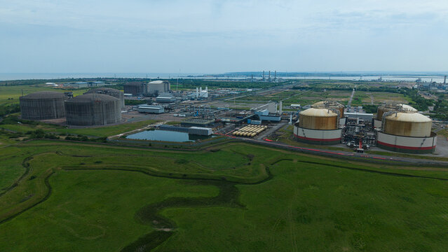Aerial view of Grain LNG terminal featuring large storage tanks and industrial infrastructure surrounded by green fields in Wallend, England, United Kingdom.