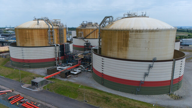 Aerial view of Grain LNG terminal featuring massive storage tanks, complex piping systems, and industrial infrastructure under an overcast sky in Wallend, England, United Kingdom.