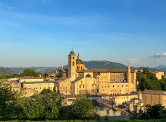 Fototapeta premium Panoramic aerial view of Urbino’s historic old town at golden hour, showcasing its Renaissance architecture, iconic landmarks, and the rolling hills of the Marche region, Italy.