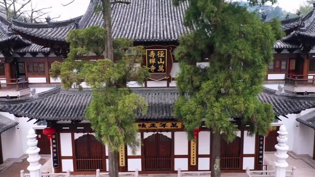 Symmetrical aerial view of a traditional Chinese temple courtyard in China featuring classical wooden halls, ancient pine trees and stone lion statues. Captures the balance and serenity of historic Ch