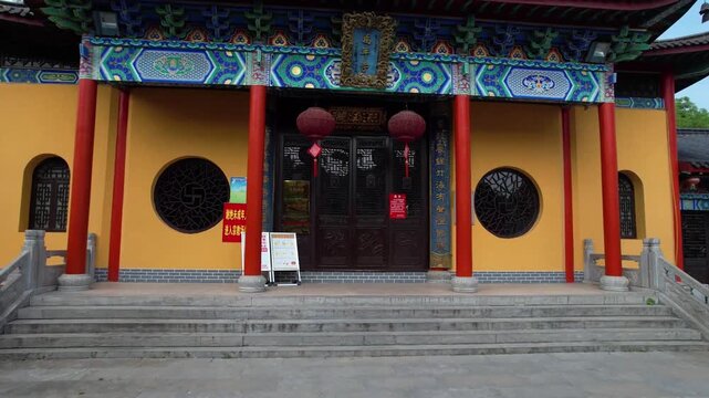 Aerial footage of a grand traditional Chinese temple entrance in China featuring vivid red pillars, blue ornamental beams and circular moon gates. Showcases the artistic detail of classical Chinese re