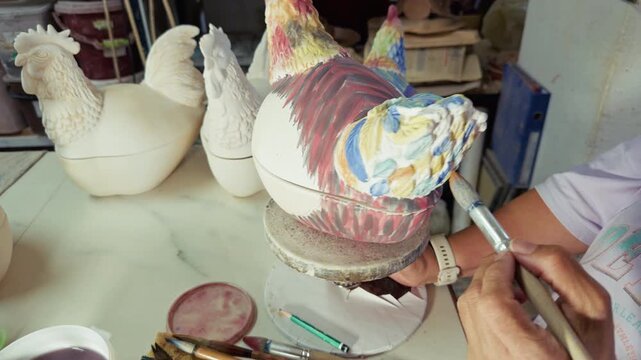 Artisan Painting Ceramic Chicken Figurine With Brush In Pottery Workshop