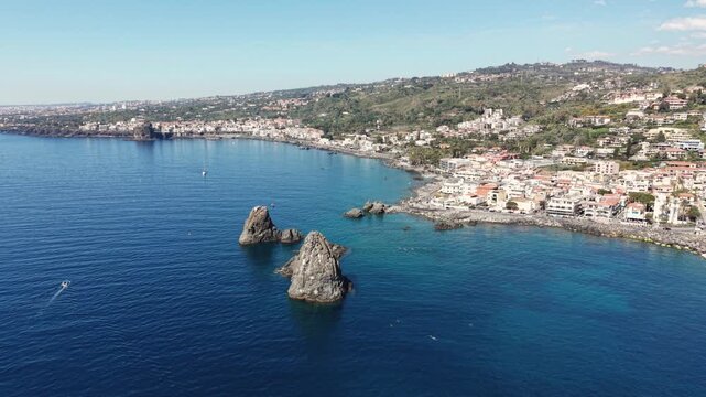 Aerial view of Islands of the Cyclops rock formations in the blue Mediterranean sea along the coastline of Aci Castello, Italy.