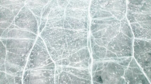 Drone view of half frozen lake with ice on water, close up view of blue ice crack and bubbles in earl spring day, top view ice floating on lake, 4k real time footage travel concept.
