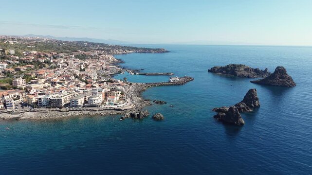 Aerial view of the volcanic Islands of the Cyclops rising from the blue Mediterranean Sea near the coastal town of Aci Castello, Italy.