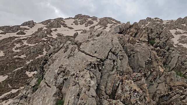 Dramatic close-up of jagged rocky mountain summit with spring snow patches scattered between rugged formations under stormy cloudy sky.
📍 Hawraman Takht, Kurdistan, Iran 