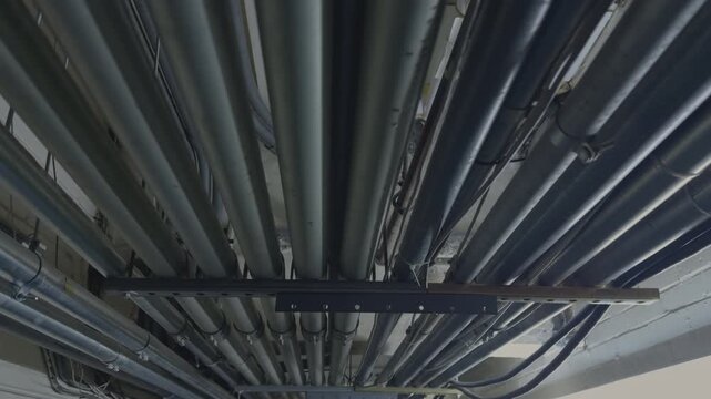 Dense Bundle of Industrial Metal Conduits and Pipes on Ceiling