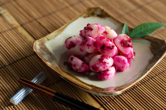 Pickled shiso bonito garlic served on a plate placed on a bamboo luncheon mat.