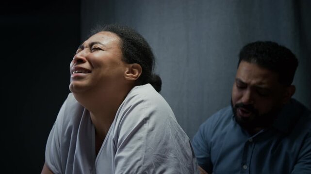 Black pregnant woman leaning on hospital bed rail,breathing through painful labor contractions while husband rubs her back. Footage suits maternity care and childbirth promotions