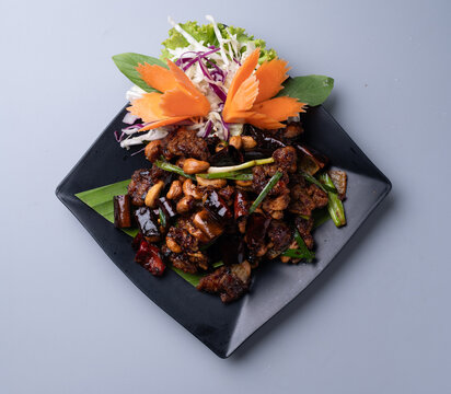 Stir fried chicken with cashew nuts and dried chili on black plate.