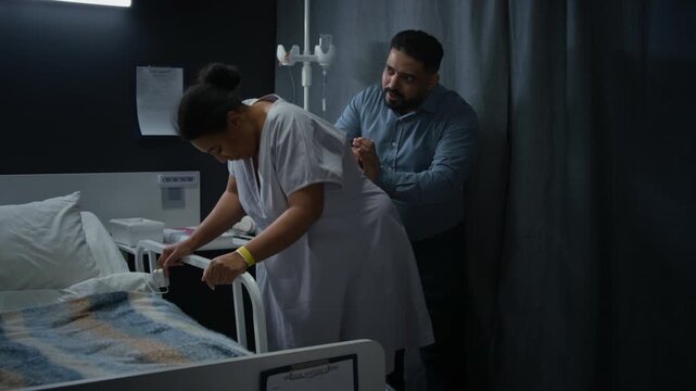 Black pregnant woman experiencing labor contractions in hospital with husband massaging her back. Video suitable for maternity care and childbirth education campaigns