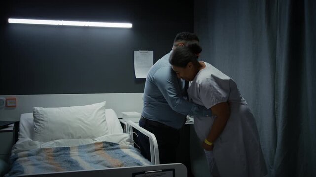 pregnant woman experiencing labor contractions in hospital,leaning on bed while husband rubs her back. Footage suitable for healthcare,childbirth education,and family planning videos