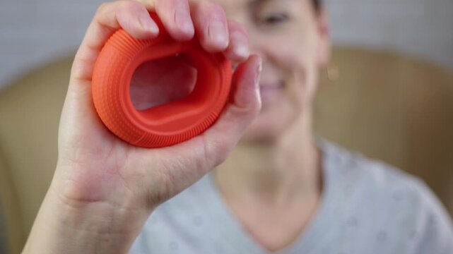 Squeezing expander for rehabilitation. Woman strengthening her hand and wrist by squeezing a rubber expander, a therapeutic exercise for rehabilitation, improving grip, and relieving stress