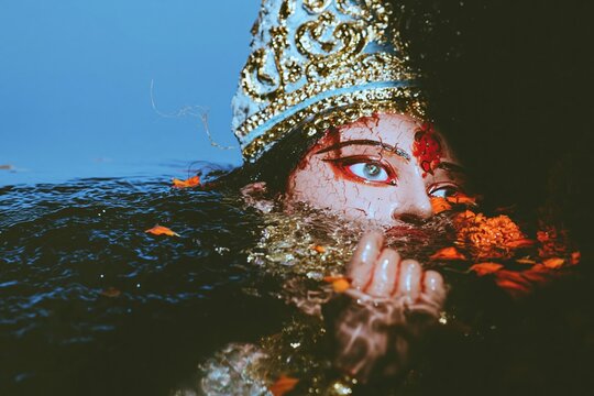 Close up of a clay Durga idol submerged in water for religious ritual during Dashami visarjan festival for cultural editorial, religious studies and documentary publishing