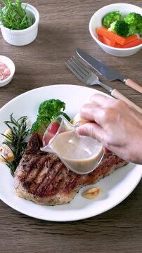 Grilled pork chop steak with baked potatoes, tomatoes and Broccoli, carrot on white plate
