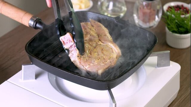 A thick pork chop is grilling until the skin is a beautiful golden color. The aroma of meat and spices fills the air. Every bite is juicy and delicious, ready to satisfy steak lovers.