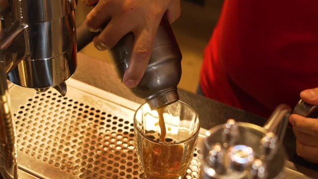 Barista in Red Uniform Pouring Fresh Espresso Shot into Iced Glass at Professional Coffee Machine, Specialty Coffee Bar Action Scene