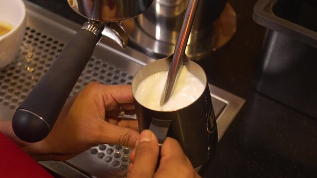 Professional Milk Steaming Technique at Stainless Steel Espresso Machine in Modern Coffee Bar