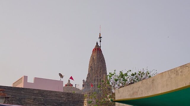 Close view of Dwarkadhish temple shikhara with red religious flag against clear sky. Perfect for Hindu devotional content, pilgrimage documentaries, India spirituality and travel projects.