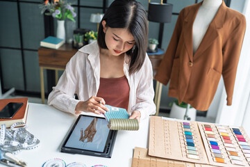 Asian woman fashion designer using tablet for digital clothing sketch digital technology creativity innovation lifestyle in fashion studio. © Charlie's