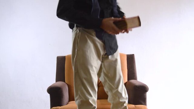 Young Man Reading a Book in Armchair