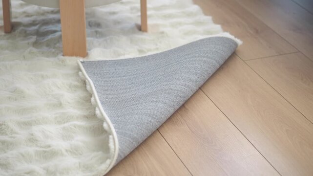 Rug partially rolled on wooden floor in living room