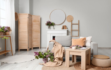 Obraz premium Interior of living room with sofa, mirror and lilac flowers