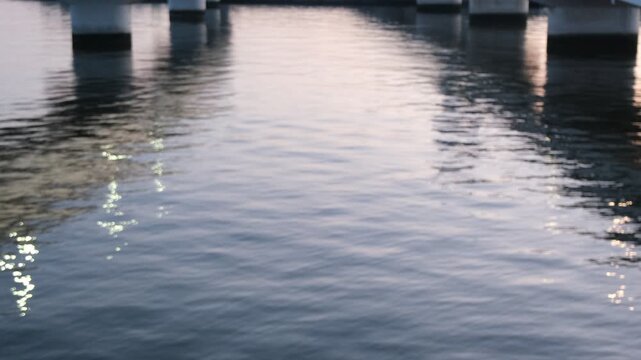 Calm Water Surface Reflecting Bridge Piers and Dusk Sky