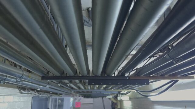 Dense Bundle of Industrial Metal Pipes and Conduits on Ceiling