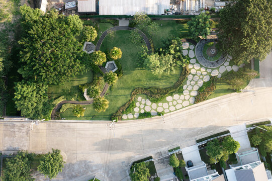 Aerial view of manicured garden landscape, winding stone pathways, lush lawns, meticulously placed flora. Highlights residential exterior design, scenic park integration, backyard landscaping.