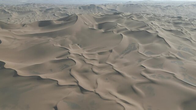 Aerial view of rippling sand dunes stretch across the Kumtag Desert, an ocean of ochre hues under a pale sky, Turpan, China.