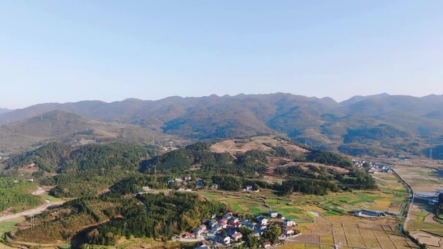 Aerial View of Rural Village and Farmland Beneath Mountain Range