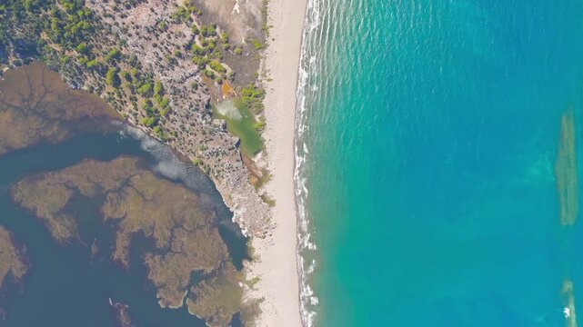 Dalyan, Turkey. Iztuzu Turtle Beach, a narrow golden sand spit separating the dark Dalyan Strait from the turquoise Mediterranean Sea, aerial top-down view. Aerial View