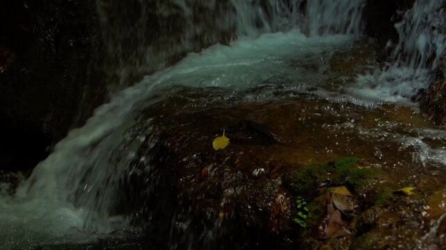 Close-up scene of a rushing forest waterfall and mossy rocks in Laos PDR